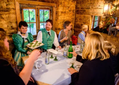 Gedeckter Tisch mit Hochzeitsgaesten in Tracht bei einer Hochzeit im Brauereigasthof Aying. Hochzeitsfotografie.