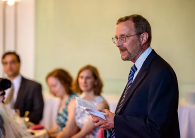 Mann haelt eine Rede bei einer Hochzeit in Ansbach, waehrend Gaeste zuhören, aufgenommen von einem Hochzeitsfotografen.