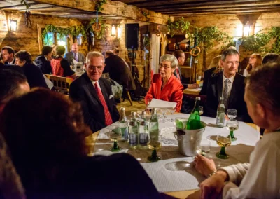 Gäste sitzen an einem Tisch bei einer Hochzeitsfeier im Brauereigasthof Aying, fotografiert von einem Hochzeitsfotografen.