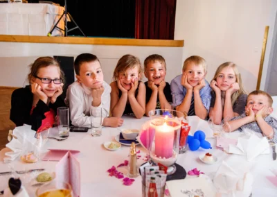 Kinder am Tisch bei Hochzeitsfeier, lächelnd. Hochzeitsfotografie im Kurhaus Bad Toelz, beeindruckende Details.