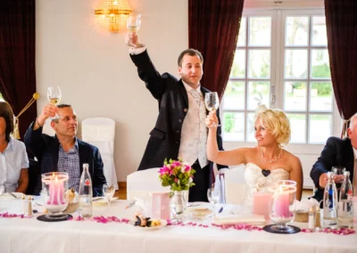 Braut und Gast erheben Glaeser bei Hochzeit im Kurhaus Bad Toelz. Hochzeitsfotografie in Oberbayern.