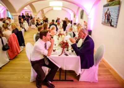 Gäste unterhalten sich bei Hochzeitsfeier in Landshut, festlich gedeckter Tisch, Hochzeit im Augustlhof Pfettrach.