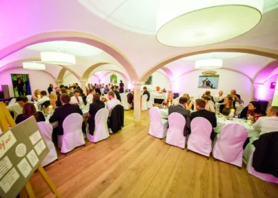 Hochzeitsgesellschaft im festlich beleuchteten Saal in Augustlhof Pfettrach bei Landshut, aufgenommen vom Hochzeitsfotografen.