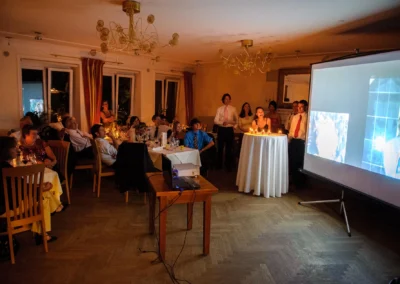 Gäste bei einer Hochzeitsfeier sehen eine Projektion an, im Hotel Langwieder See. Hochzeitsreportage München.