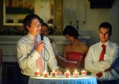 Mann haelt Rede bei Hochzeit, Kerzen auf Tisch, Hochzeitsfoto aufgenommen im Hotel Langwieder See westlich von Muenchen.