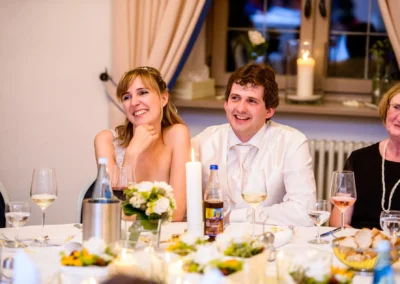 Lächelndes Hochzeitspaar mit Gästen bei Kerzenschein, aufgenommen nahe Ingolstadt. Hochzeitsfotografie im Schloss Grünau.