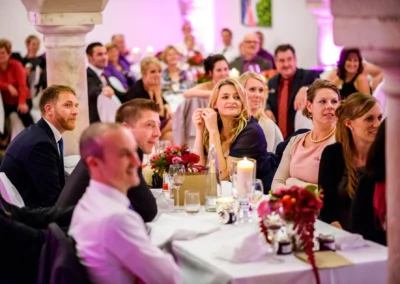 Gäste sitzen an einem Tisch bei einer Hochzeitsfeier in Landshut, festgehalten von einem Hochzeitsfotografen.