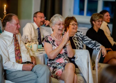 Gäste lachen bei einer Hochzeitsfeier in der Orangerie Ansbach, festgehalten in einem Hochzeitsfoto.