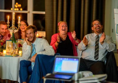 Gaste lachen bei einer Hochzeitsfeier in der Orangerie Ansbach. Hochzeitsfoto zeigt froehliche Momente.