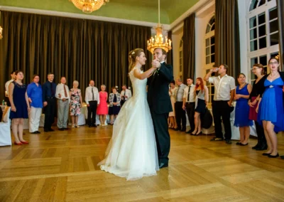 Brautpaar tanzt den Hochzeitswalzer in der Orangerie Ansbach, umgeben von Gaesten, elegantes Ambiente.