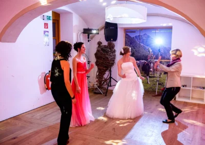 Braut in weissem Kleid tanzt mit drei Frauen in farbigen Kleidern bei Hochzeit in Augustlhof Pfettrach. Hochzeitsfoto.