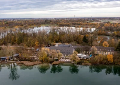 Luftaufnahme von Hotel und Restaurant Langwieder See, Herbstfarben spiegeln sich im ruhigen Wasser für Hochzeitsfotos.