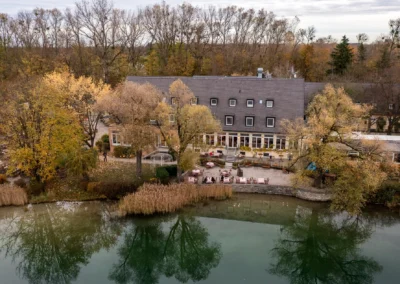 Außenansicht des Hotels am Langwieder See im Herbst, umgeben von Bäumen, ideal für eine Hochzeitsreportage.