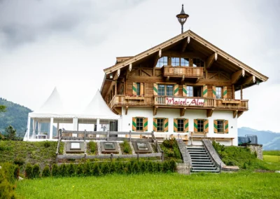 Holzchalethaus Maierl Alm in Kirchberg in Tirol mit markanter Treppe, grüne Bergkulisse.