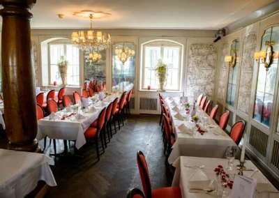 Elegantes Hochzeitstafel im Restaurant in München-Nymphenburg, mit rot gepolsterten Stühlen und weißen Tischdecken.
