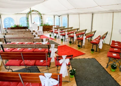 Hochzeitsfoto einer festlich dekorierten Trauung mit roten Kissen im Buchscharner Seewirt am Starnberger See.