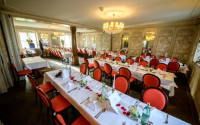 Festlich dekorierter Raum mit weißen Tischdecken, roten Stühlen, Blumen und Kerzen in München Nymphenburg