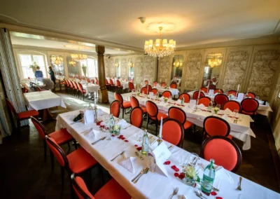 Elegante Hochzeitstafel mit roten Stühlen und Kerzen in der Schlossschänke Schwaige München-Nymphenburg. Hochzeitsfoto.