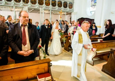 Priester führt Brautpaar bei kirchlicher Trauung in Kirche in Kirchheim. Hochzeitsfotografie nahe Muenchen.