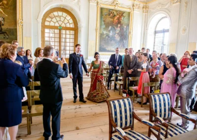 Brautpaar steht bei standesamtlicher Trauung im Schloss Schleissheim vor Gästen. Hochzeitsfoto mit Hochzeitsgesellschaft.