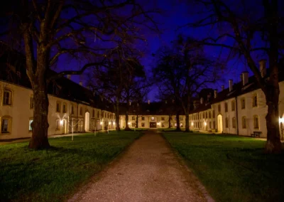 Nächtliche Ansicht eines beleuchteten Innenhofs bei einer Hochzeit in München-Nymphenburg, umgeben von Bäumen.