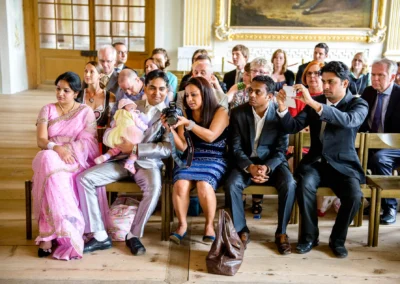 Gäste bei standesamtlicher Trauung in Schleissheim. Hochzeitsfotografie mit buntem Publikum und Kamera im Vordergrund.