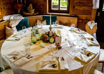 Festlich gedeckter Hochzeitstisch mit Blumengesteck, Kerze und Gläsern. Aufgenommen bei Hochzeit im Buchscharner Seewirt.