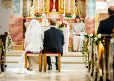 Brautpaar sitzt bei kirchlicher Trauung nahe Muenchen vor dem Altar, Fotografiert von Hochzeitsreportage.