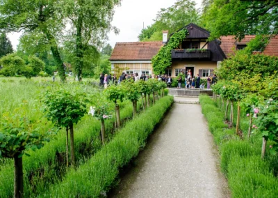Hochzeitsgesellschaft am Künstlerhaus Gasteiger am Ammersee, umgeben von Natur und Grün, bei einer Hochzeitsfeier.