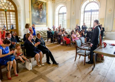 Standesamtliche Trauung im Schloss Schleissheim. Brautpaar steht vor applaudierenden Gaesten. Hochzeitsfotografie.