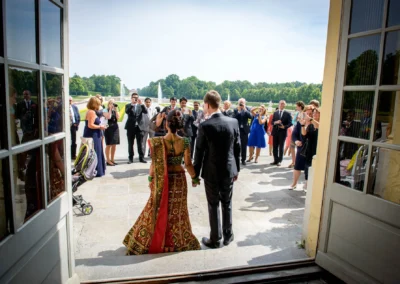 Brautpaar bei standesamtlicher Trauung im Schloss Schleissheim, umgeben von Gratulanten und Fotografen.