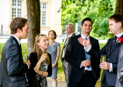Gäste in eleganter Abendgarderobe bei einer Hochzeit im Schlosspark Schleissheim nahe München. Hochzeitsreportage.