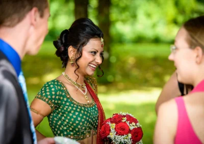 Frau im traditionellen Kleid, laechelt mit Blumenstrauss bei Hochzeit im Schlosspark Schleissheim, nördlich Muenchen.