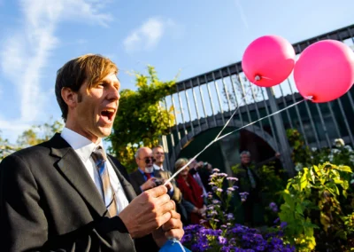 Mann im Anzug mit roten Luftballons bei Hochzeit in alter gaertnerei Taufkirchen nahe Muenchen, Hochzeitsfoto.
