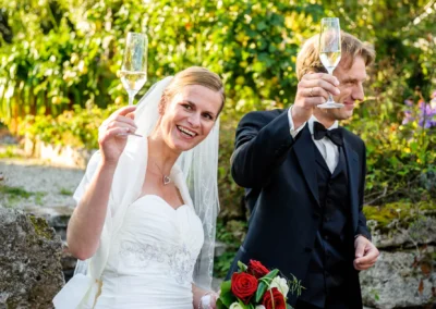Brautpaar hebt Sektglas zum Anstoßen bei Hochzeit in der alten gaertnerei Taufkirchen nahe Muenchen hoch.