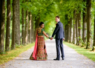 Brautpaar in traditioneller Kleidung bei Hochzeitsfotos im Schlosspark Schleissheim, Blick zurück über die Schulter.
