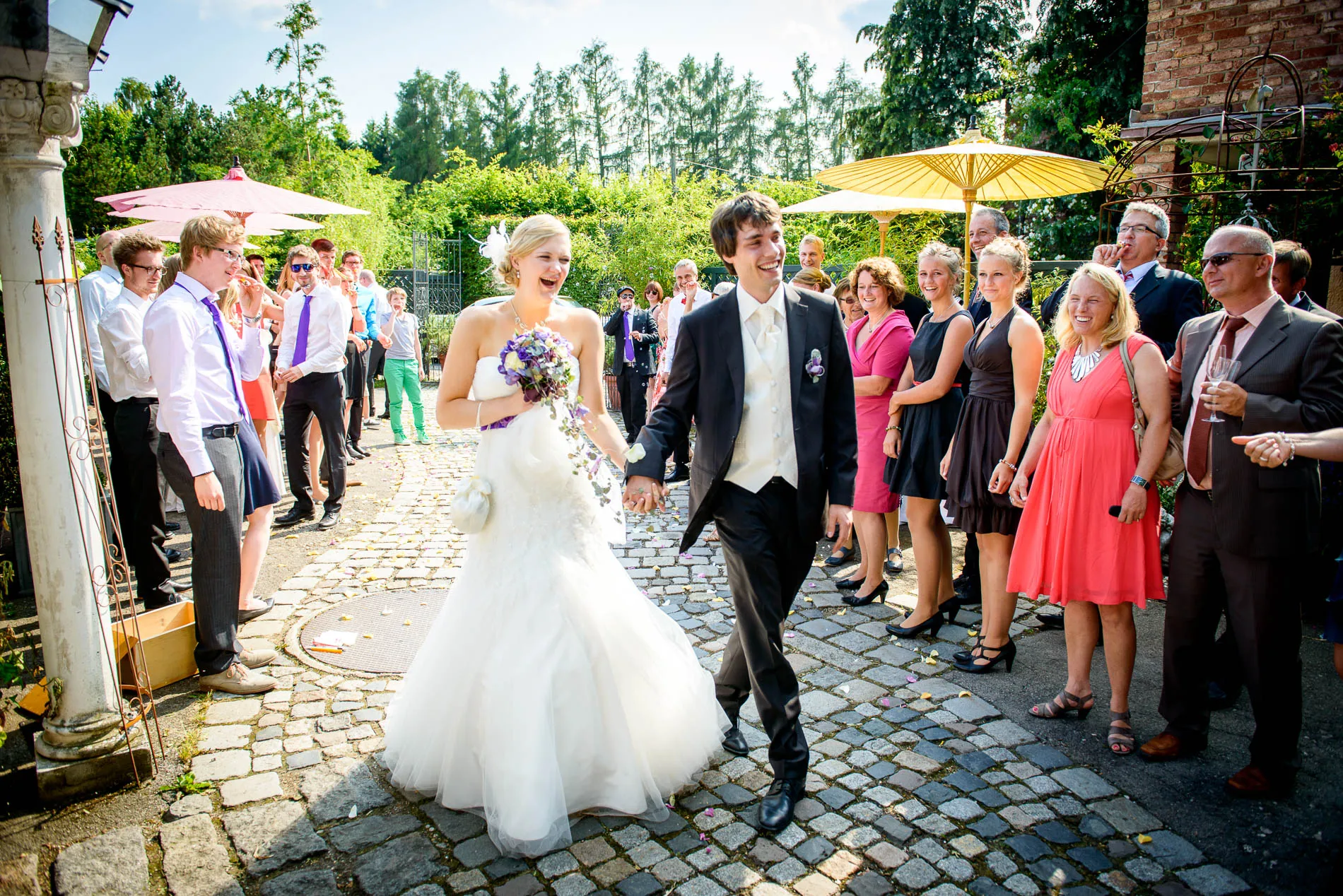 Brautpaar laechelt nach der Trauung vor Gaesten. Hochzeitsreportage in der alten Gaertnerei Taufkirchen.