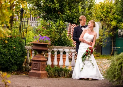 Brautpaarposiert im Garten, umgeben von gruenen Pflanzen, bei Hochzeit in Taufkirchen nahe Muenchen.