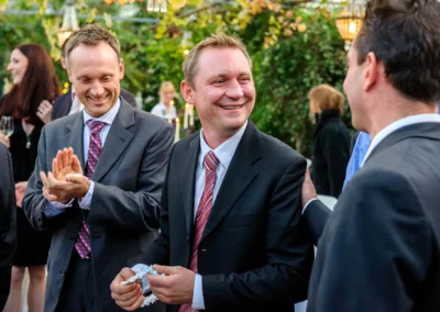 Gruppe lachender Hochzeitsgaeste in Anzug bei einer Hochzeitsfeier nahe Muenchen. Hochzeitsreportage von Taufkirchen.