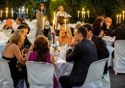 Gäste bei Hochzeit in Taufkirchen an runden Tischen, Kerzenleuchter, festliche Atmosphäre im Freien. Hochzeitsreportage.