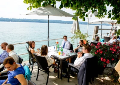 Gäste bei einer Hochzeit am Starnberger See, genießen die Aussicht bei Seehotel Leoni. Hochzeitsreportage in Bayern.