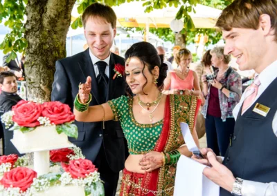 Braut und Bräutigam schneiden Hochzeitstorte im Seehotel Leoni bei südlich Muenchen an. Hochzeitsfotografie.