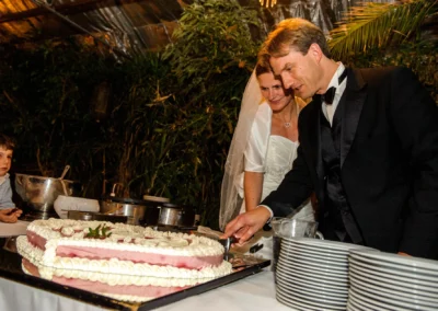 Brautpaar schneidet Hochzeitstorte an, begleitet von einem Kind; Hochzeitsreportage in Taufkirchen bei Muenchen.