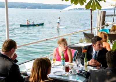 Hochzeitsfeier am Seehotel Leoni, Gaeste sitzen am Tisch mit Blick auf den Starnberger See. Hochzeitsreportage.