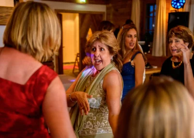 Gäste tanzen ausgelassen in festlicher Abendkleidung, die Stimmung wirkt fröhlich und ausgelassen in einem warm beleuchteten Raum.