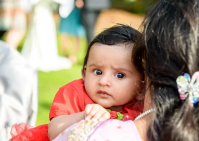 Baby in rotem Outfit bei Hochzeit im Seehotel Leoni. Hochzeitsfoto im Freien, nahe Starnberger See, suedlich Muenchen.