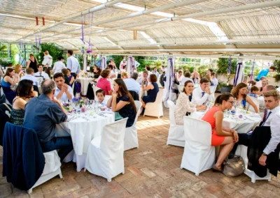 Gäste sitzen an weiß gedeckten Tischen in einem lichtdurchfluteten Raum, unterhaltend und entspannt.