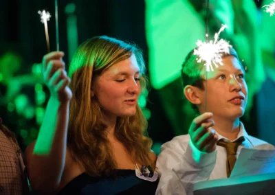 Zwei Kinder halten Wunderkerzen in einem festlich beleuchteten Raum, sie wirken fröhlich und konzentriert.
