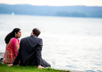 Paar bei Hochzeit im Seehotel Leoni am Starnberger See, sitzt am Ufer mit Blick aufs Wasser. Hochzeitsfoto im Freien.