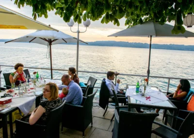 Gaste geniessen bei einer Hochzeit im Seehotel Leoni am Starnberger See speisen mit Blick auf das Wasser.